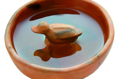 Moderní replika misky s kachničkou napuštěná vodou; obrázek evokuje způsob užívání předmětu, jehož fragment pochází ze zahloubené chaty z doby římské zkoumané ve Slavkově u Brna.